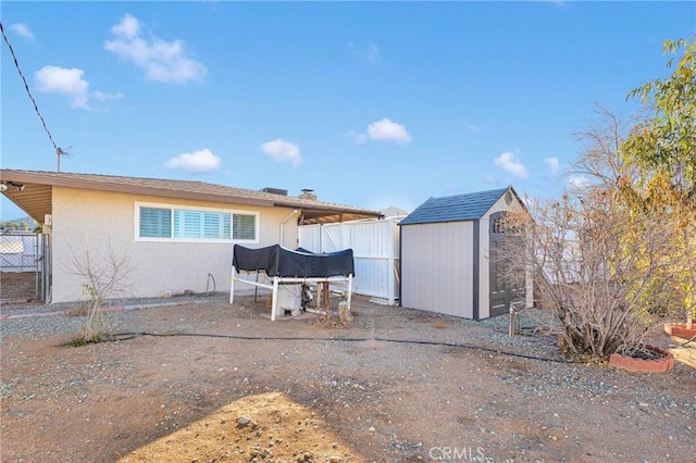 back of house with a storage unit