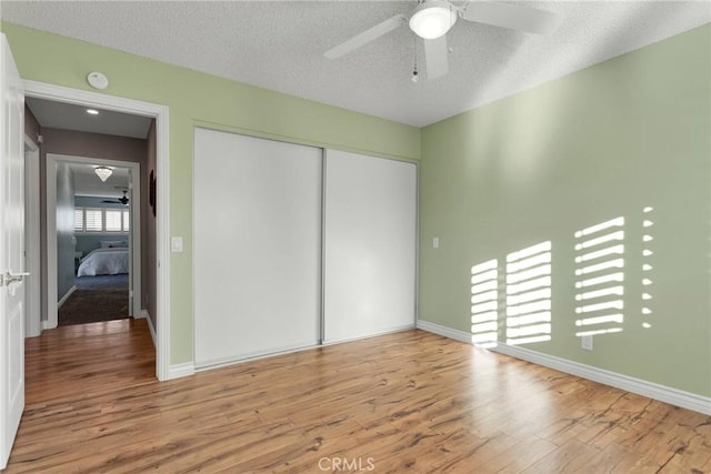 unfurnished bedroom with ceiling fan, light hardwood / wood-style flooring, a textured ceiling, and a closet