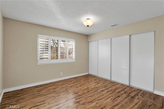 unfurnished bedroom with a textured ceiling, hardwood / wood-style flooring, and a closet