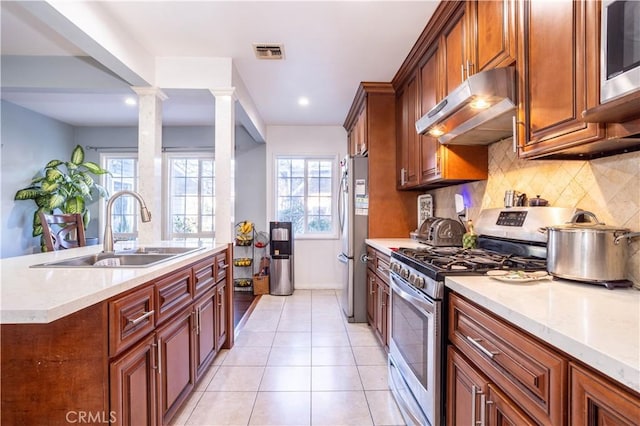 kitchen featuring sink, stainless steel appliances, tasteful backsplash, decorative columns, and light tile patterned floors