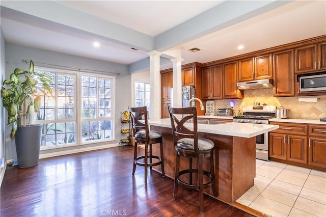 kitchen featuring sink, a breakfast bar, appliances with stainless steel finishes, tasteful backsplash, and an island with sink