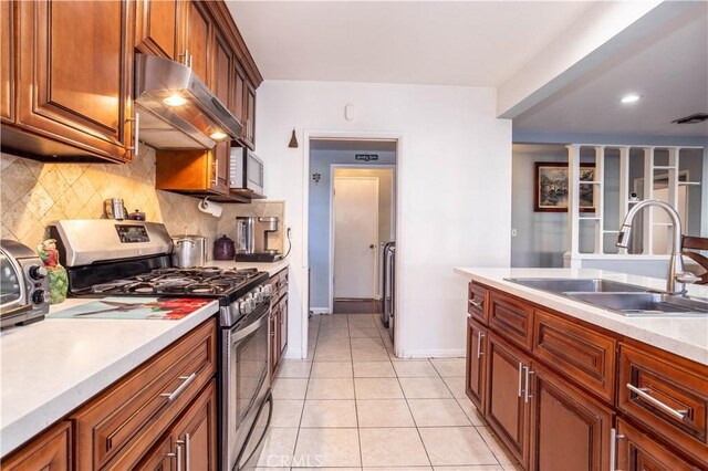 kitchen featuring backsplash, sink, light tile patterned floors, and appliances with stainless steel finishes