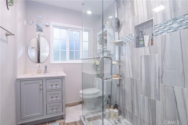 bathroom featuring vanity, toilet, and a shower with door