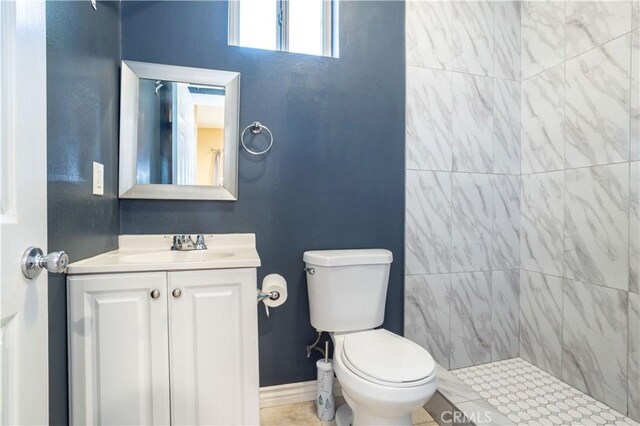 bathroom with tiled shower, vanity, and toilet