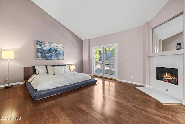 bedroom featuring dark wood-type flooring, access to exterior, and high vaulted ceiling