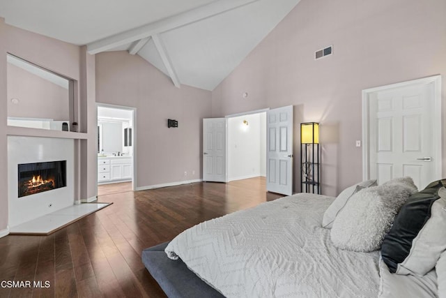 bedroom featuring beamed ceiling, ensuite bathroom, dark hardwood / wood-style floors, and high vaulted ceiling