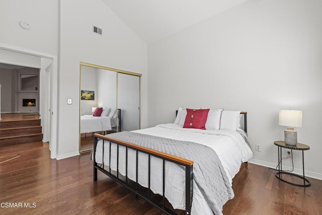 bedroom featuring dark wood-type flooring, high vaulted ceiling, and a closet