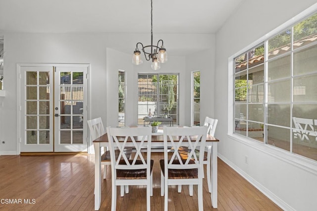 dining space with french doors, wood-type flooring, and a chandelier