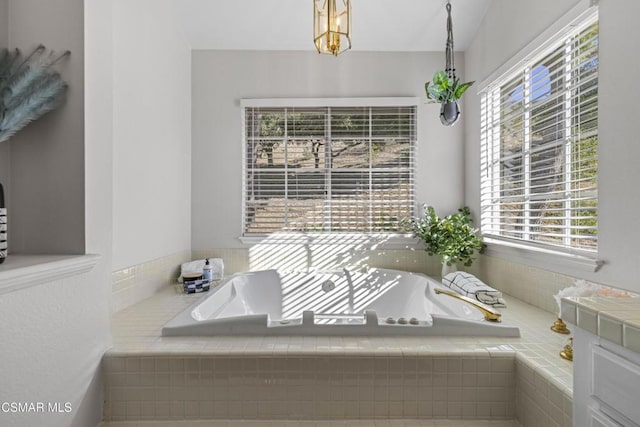 bathroom featuring tiled tub and vanity