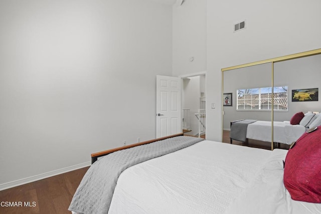 bedroom featuring dark wood-type flooring, a closet, and a high ceiling