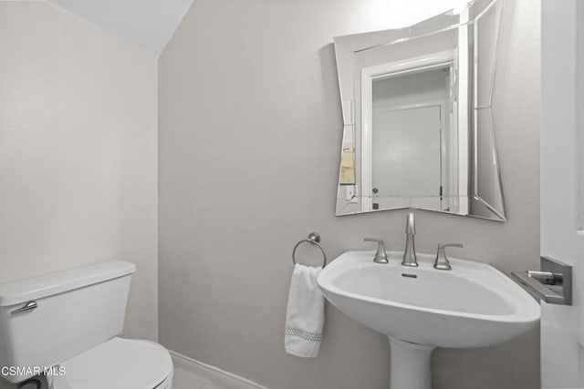 bathroom featuring sink, vaulted ceiling, and toilet