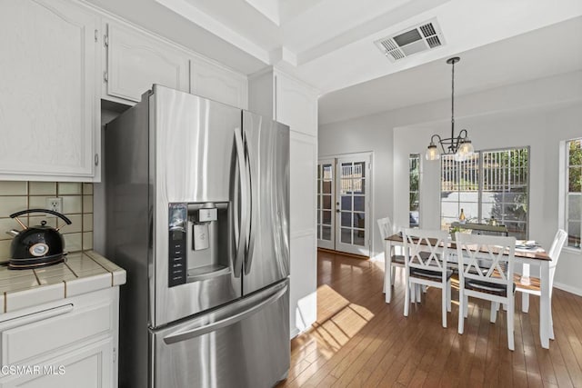 kitchen with stainless steel fridge, tile countertops, and white cabinets