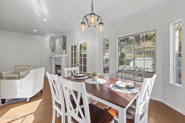 dining room featuring dark hardwood / wood-style floors, a healthy amount of sunlight, a fireplace, and a notable chandelier