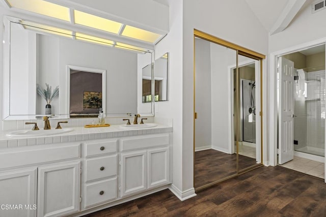 bathroom with vanity, lofted ceiling, hardwood / wood-style floors, and walk in shower