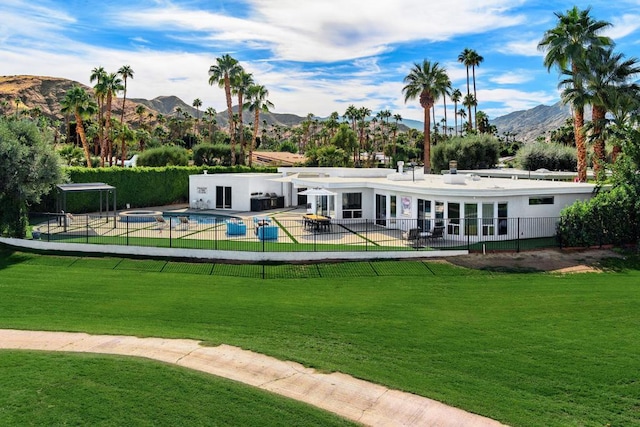 rear view of property featuring a mountain view, a yard, and a fenced in pool