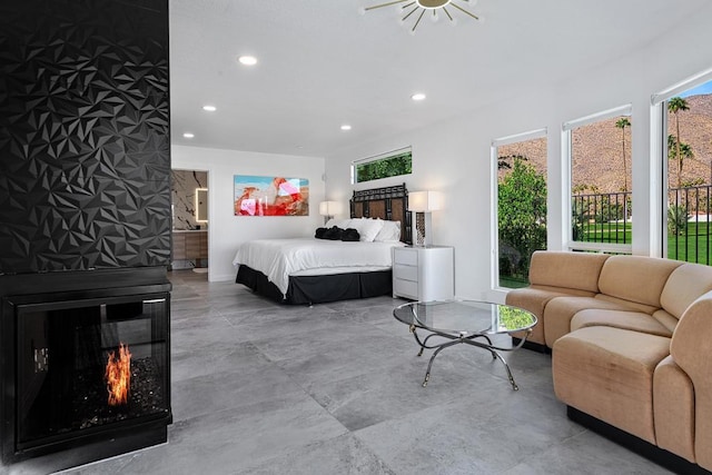 bedroom featuring a large fireplace, access to outside, and connected bathroom