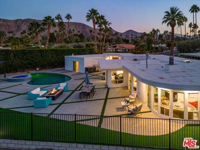 pool at dusk with a patio area, a mountain view, an in ground hot tub, and an outdoor fire pit