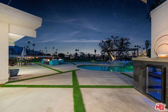 pool at dusk featuring a bar and a patio