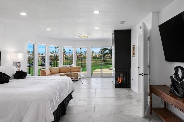 bedroom with access to exterior, multiple windows, and a multi sided fireplace