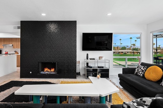 living room with a large fireplace and light tile patterned flooring