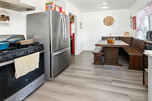 kitchen featuring wall chimney exhaust hood, light hardwood / wood-style flooring, and appliances with stainless steel finishes