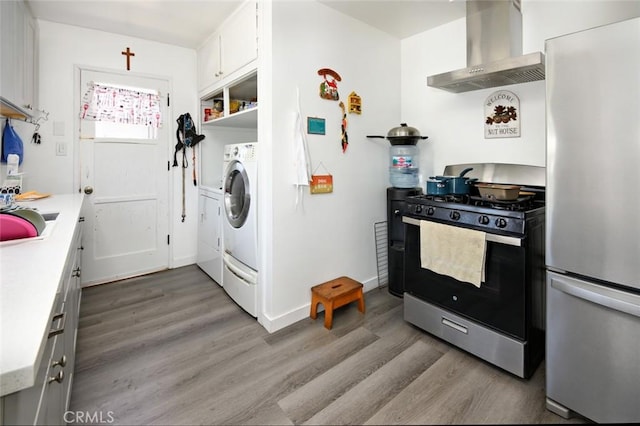 kitchen featuring white cabinetry, light hardwood / wood-style flooring, wall chimney exhaust hood, and appliances with stainless steel finishes