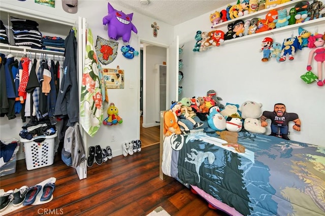 bedroom with a textured ceiling, a closet, and dark hardwood / wood-style flooring