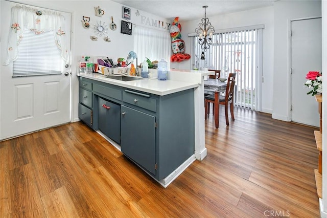 kitchen featuring kitchen peninsula, pendant lighting, a notable chandelier, and dark hardwood / wood-style flooring