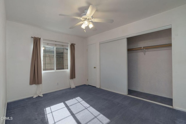 unfurnished bedroom with dark colored carpet, a closet, and ceiling fan