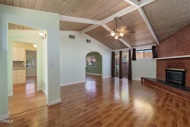 unfurnished living room with a brick fireplace, wood ceiling, ceiling fan, lofted ceiling with beams, and hardwood / wood-style floors