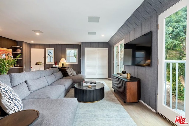 living room featuring a wealth of natural light, wooden walls, and light hardwood / wood-style floors