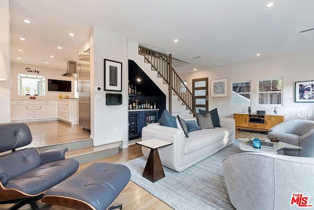 living room featuring bar area, beverage cooler, and light hardwood / wood-style flooring