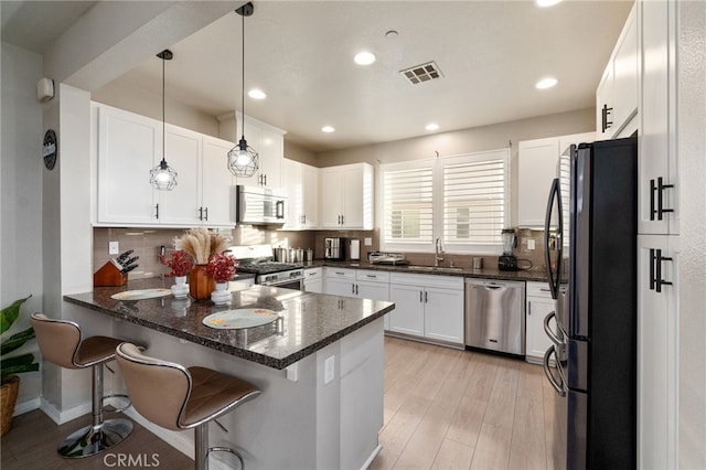 kitchen featuring appliances with stainless steel finishes, sink, white cabinets, hanging light fixtures, and kitchen peninsula