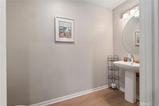 bathroom with a sink, baseboards, and wood finished floors