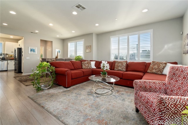 living room with light wood-type flooring, visible vents, and recessed lighting