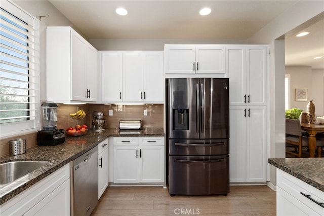 kitchen featuring dark stone counters, stainless steel appliances, and white cabinetry