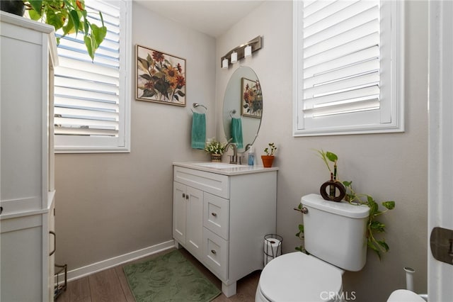 bathroom with baseboards, vanity, toilet, and wood finished floors