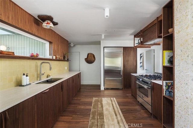 kitchen with decorative backsplash, high quality appliances, sink, and dark hardwood / wood-style flooring