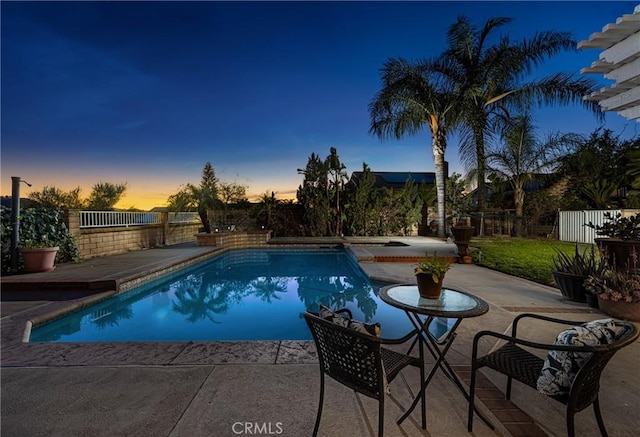 pool at dusk featuring a patio