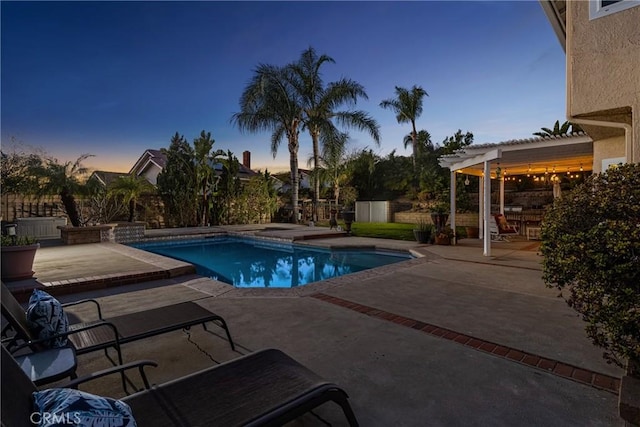 pool at dusk featuring a patio, a jacuzzi, and a pergola