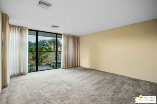 unfurnished room featuring floor to ceiling windows and carpet