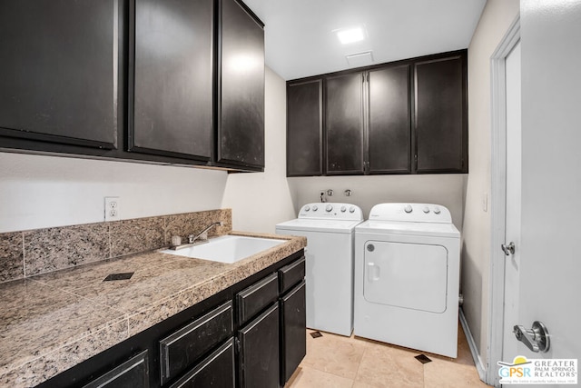 laundry area with washer and clothes dryer, sink, light tile patterned floors, and cabinets