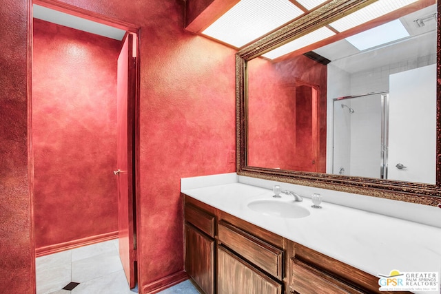 bathroom featuring tile patterned floors, a skylight, a shower with door, and vanity