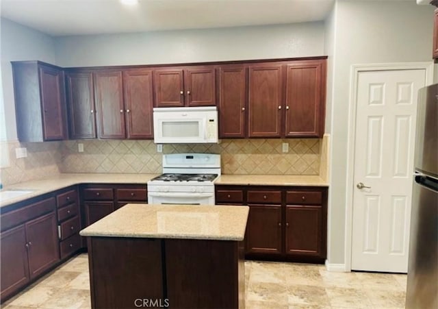 kitchen featuring white appliances, sink, tasteful backsplash, a kitchen island, and light stone counters