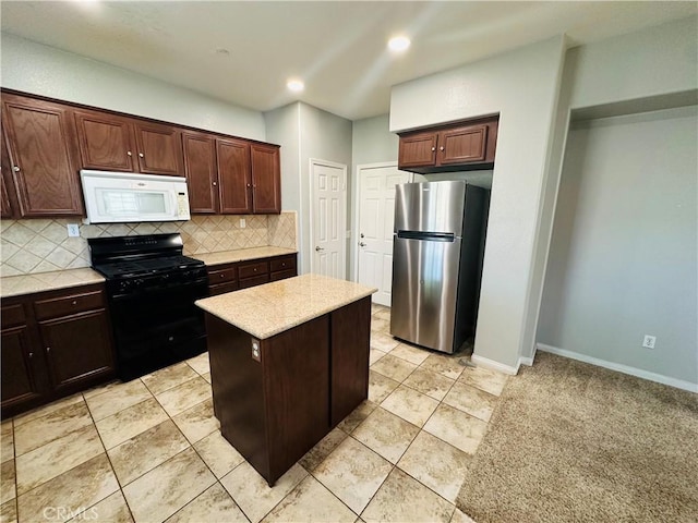 kitchen with black gas range oven, tasteful backsplash, stainless steel fridge, a center island, and dark brown cabinetry