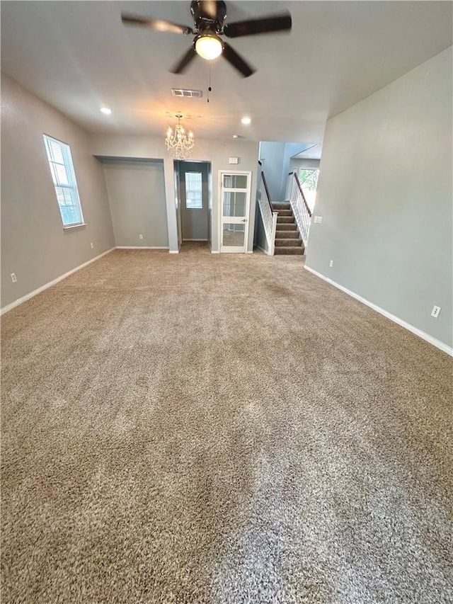 unfurnished living room featuring ceiling fan with notable chandelier and carpet