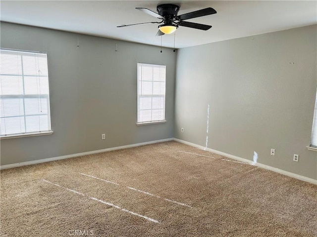 carpeted empty room with ceiling fan and plenty of natural light