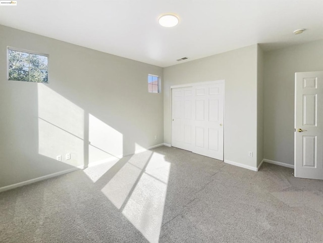 unfurnished bedroom with carpet floors, a closet, and multiple windows