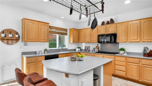 kitchen with sink, a center island, a kitchen bar, decorative backsplash, and black appliances