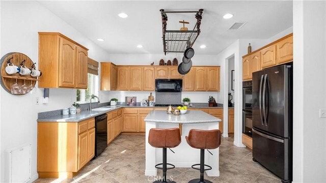 kitchen with a kitchen island, black appliances, a kitchen breakfast bar, and sink